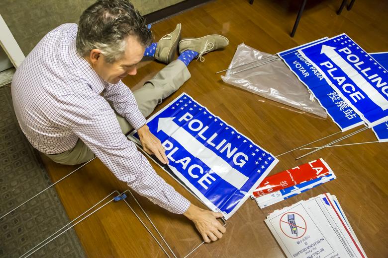 Poll worker Eric Johnson assembles outdoor signs for the polling place at Sierra 2 Center in Sacramento. Johnson and other poll workers arrive at 6 a.m. for set-up to be ready when doors open to voters at 7 a.m.