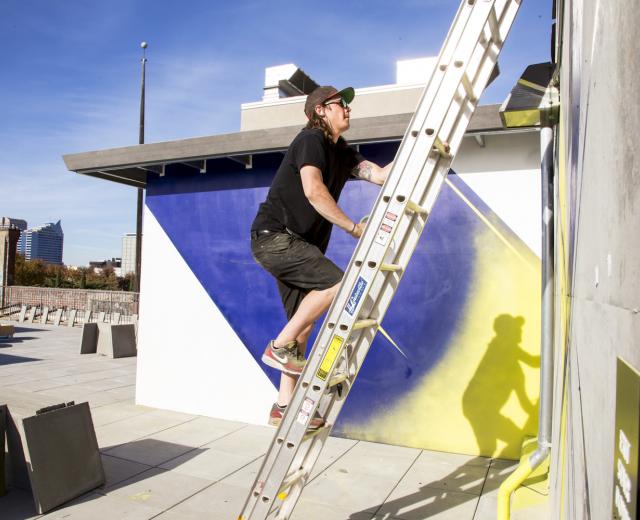 Jake Castro paints a mural on the rooftop of the Warehouse Artists Lofts in 2014. Castro is one of four Sacramento artists commissioned for the Sacramento Mural Festival. He will install his mural at the Crest Theater.