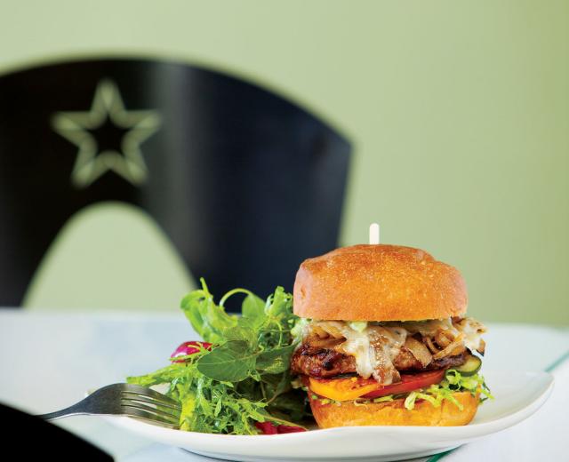 Grass-fed New Zealand beef burger with caramelized onions, Manchego cheese, pickled cucumber, tomato and aioli