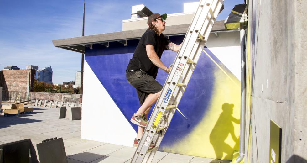 Jake Castro paints a mural on the rooftop of the Warehouse Artists Lofts in 2014. Castro is one of four Sacramento artists commissioned for the Sacramento Mural Festival. He will install his mural at the Crest Theater.