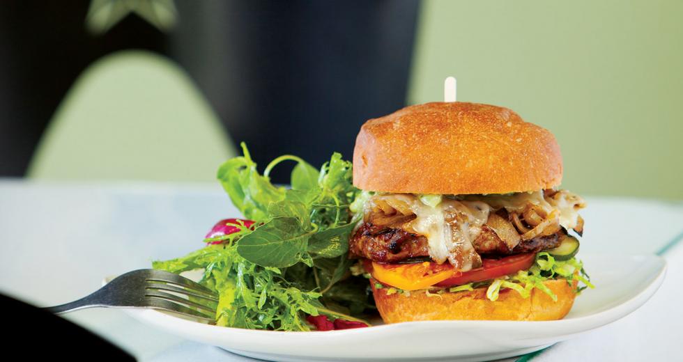 Grass-fed New Zealand beef burger with caramelized onions, Manchego cheese, pickled cucumber, tomato and aioli