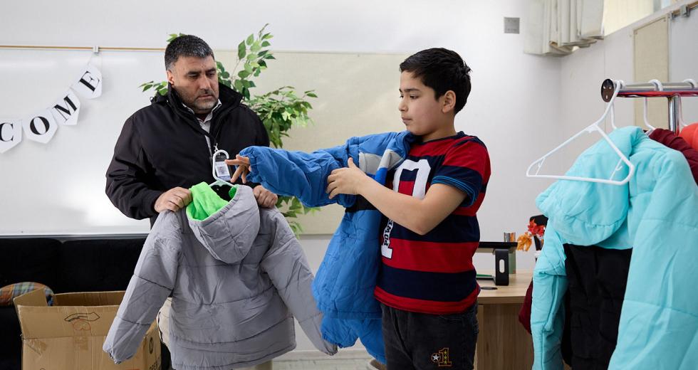 Abdul Basir, a lawyer now helping fellow Afghans resettle in Sacramento, helps a boy choose a donated winter coat. (Photos by Fred Greaves)