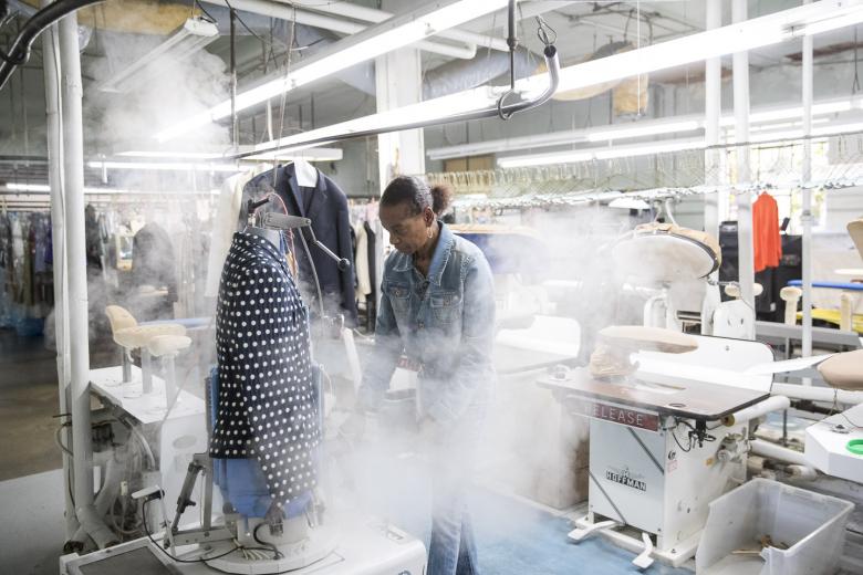 Valarie Phillips steams a garment at Woodard-Ficetti Cleaners in Sacramento. Next she will press it. The long-time employee isn't a fan of pressing because of the slow, repetitive motions: “It’s tedious and I’m standing still too long in one place.”