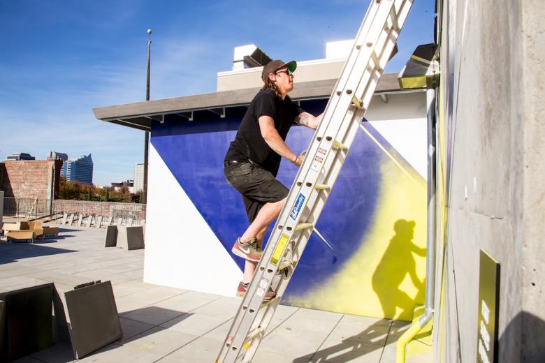 Artist Jake Castro climbs the rooftop to finish his geometric mural Artist Jake Castro climbs the rooftop to finish his geometric mural