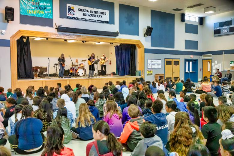 A Blues in the Schools contingent — Ilene McHolland on cello/violin, Larry Schiavone on drums, Lisa Phenix on guitar and Bas Vosen on bass — performs before about 250 students in April at Sacramento’s Sierra Enterprise Elementary School. (Photo by Steve Martarano)