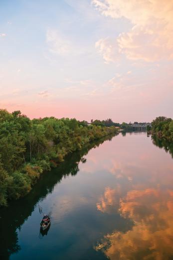 On the border of Sacramento State standing on the Guy West Bridge you can see great views of the American River. Seen here is a lone fisherman on a summer evening scouting for a catch.