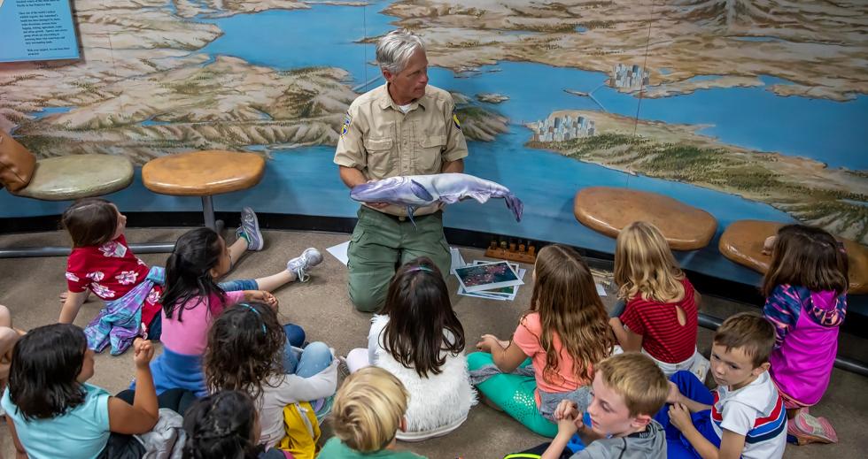 Brian Gilmore, a California Department of Wildlife scientific aide, displays the wonders of salmon biology to a group of school children at the Nimbus Visitor’s Center. (Photo by Steve Martarano)