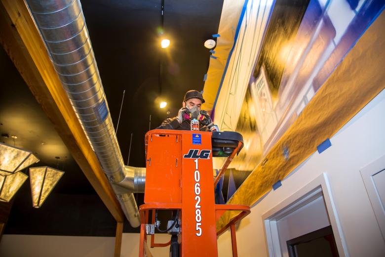 Muralist John Horton spray paints the walls of the community room Muralist John Horton spray paints the walls of the community room