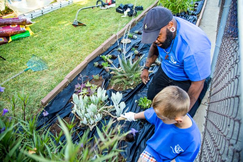 Leonardo Hutchison, district loss prevention manager for Monument Security, demonstrates how to plant flowers as he works with his volunteer team on house-painting and landscaping during Paint the Town.
Leonardo Hutchison, district loss prevention manager for Monument Security, demonstrates how to plant flowers as he works with his volunteer team on house-painting and landscaping during Paint the Town.