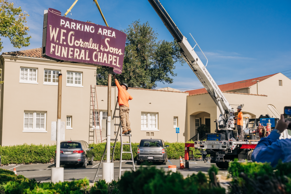 A crane helps lower the scroll-shaped sign from its posts. (Photo by Francisco Chavira)