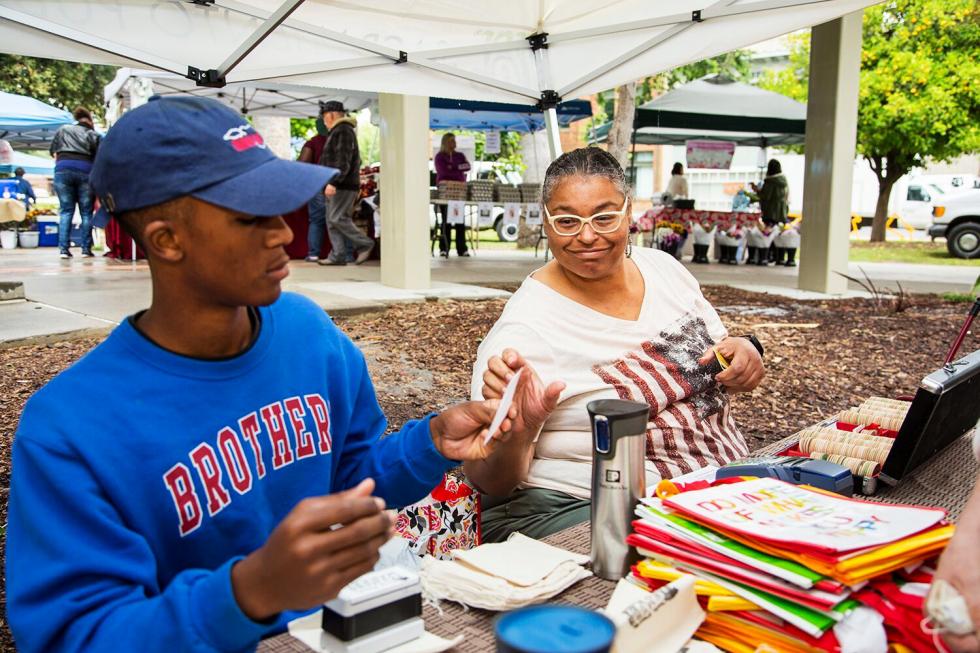 Market Manager Joany Titherington (right) and William Ervin, an intern, administer a dollar-for-dollar match of CalFresh benefits used at the Oak Park Farmers Market. 