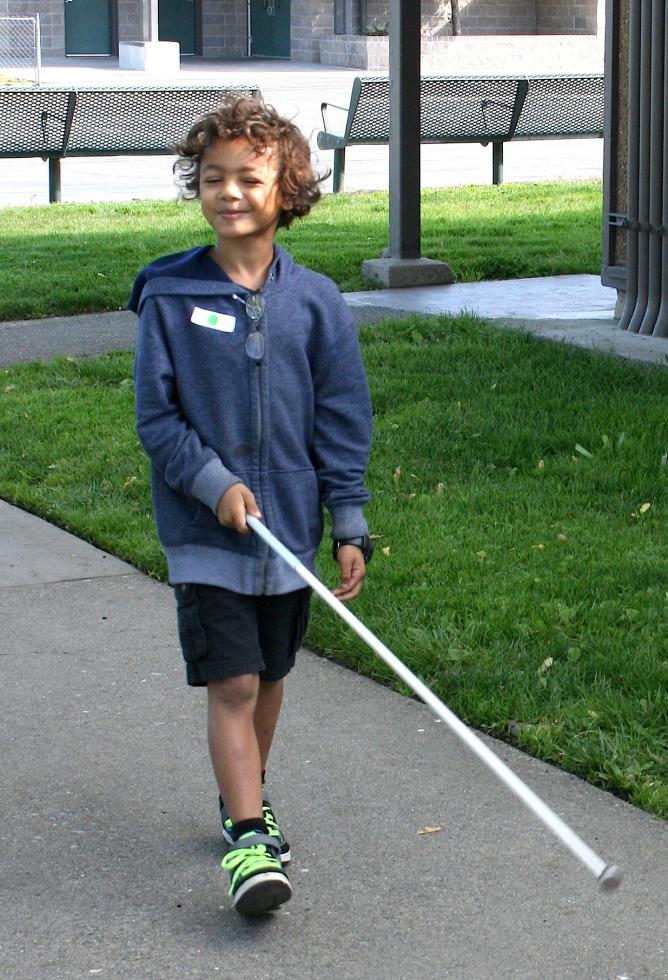 A boy learns to use a white mobility cane while walking with his eyes closed during a workshop held by A Touch of Understanding. (Photo courtesy Meghan Adamski)
