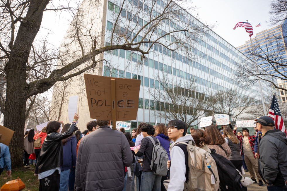 A protester holds a sign reading "We are not a police state" while standing in front of the John E. Moss federal building.