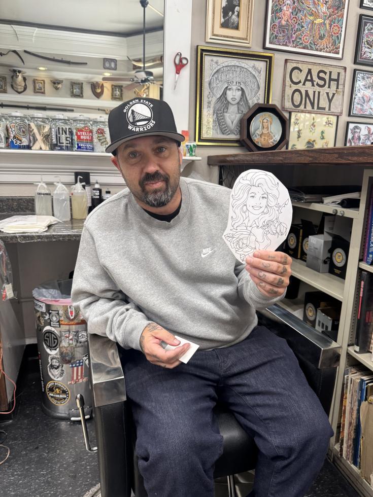 Tattoo artist Jeremy Joseph “Swype” Reser shows off the template he used for a recent Dolly Parton Tattoo at Midtown’s Royal Peacock Tattoo Parlour on Tuesday, Sept. 15. (Photo by Helen Harlan)