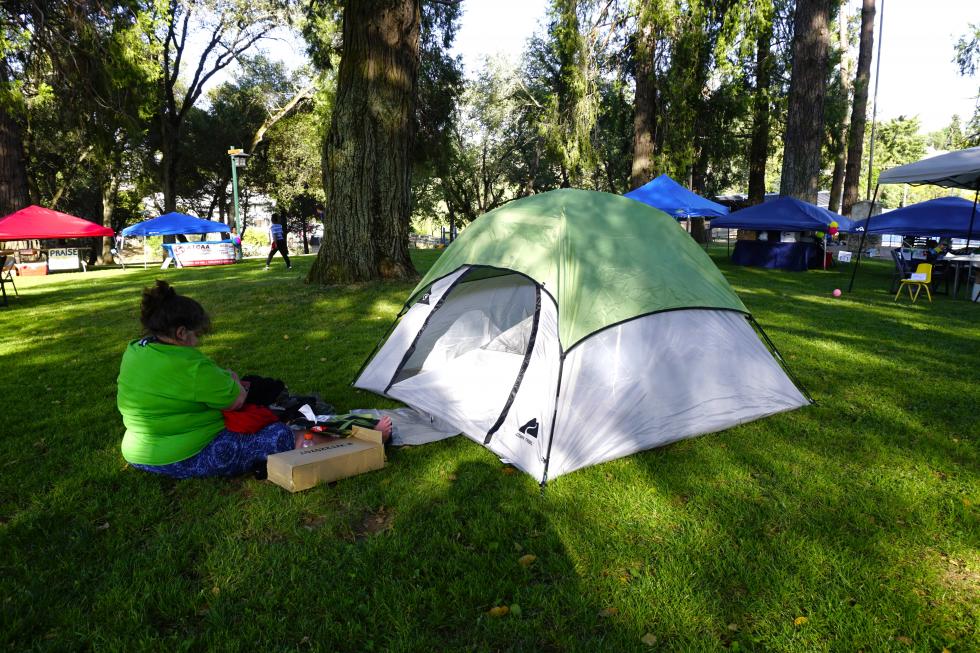 Lisa relaxes in the shade of the park’s cedar trees while her friend Richard rests inside a tent in the park, something not normally permitted by the city of Jackson.