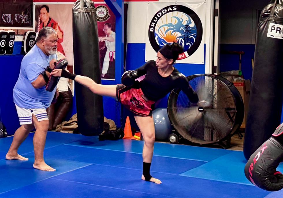 “Master Mike” McKenzie holds pads as Yaw-Yan fighter Christina Almeida practices a kick. (Photo by Scott Thomas Anderson)