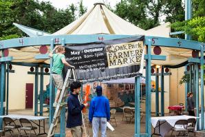 Luke Spates, of NeighborWorks Sacramento, raises the banner for the Oak Park Farmers Market as it opens its seventh season in McClatchy Park.
