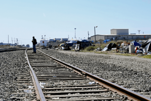 A man walks the rail road tracks along the edge of a homeless encampment where he stays. June 12, 2019. (Photo by Kate Cimini, CalMatters)