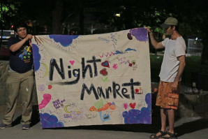 Volunteers Ethan Mouloudj and Max Morgan display a hand-painted Night Market banner. (Photos by Jennifer Fergesen)
